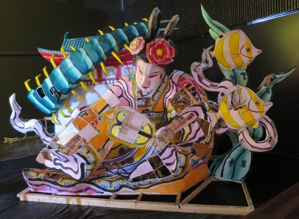 Una carroza iluminada nebuta expuesta en el interior del Nebuta Museo Wa Rasse, que muestra a una mujer con un kimono estampado, un pez grande y criaturas marinas arremolinadas.