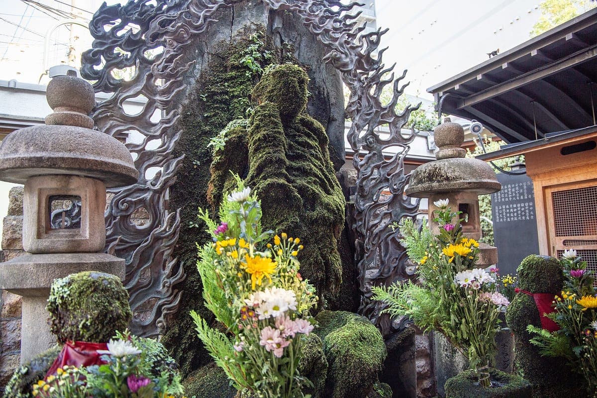 Ang estatwa ng Mizukake Fudō sa Hōzen-ji na natatakpan ng makapal na berdeng lumot, na may mga batong parol at sariwang bulaklak sa harap nito