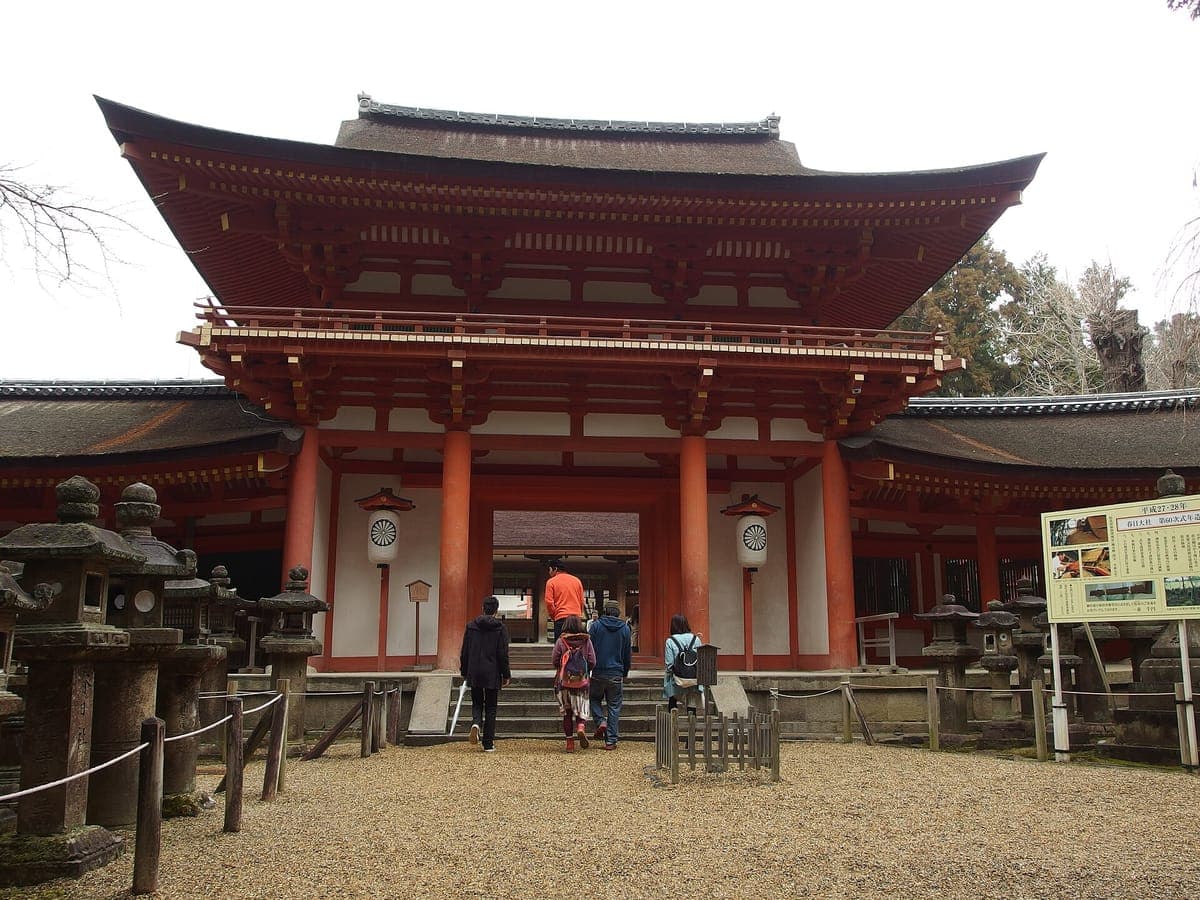 Kasuga Taisha ၏ ရှေ့တွင် ကျောက်မီးအိမ်များ တပ်ဆင်ထားပြီး ဧည့်သည်များ လှေကားထစ်များ ပေါ်တက်သည့် နှစ်ထပ် ဟင်္သပဒါးရောင် Nanmon တံခါး၊
