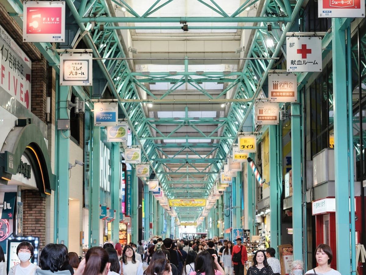 La galería comercial cubierta Sun Road en Kichijōji con un techo de acero verde, carteles colgantes y multitudes de compradores
