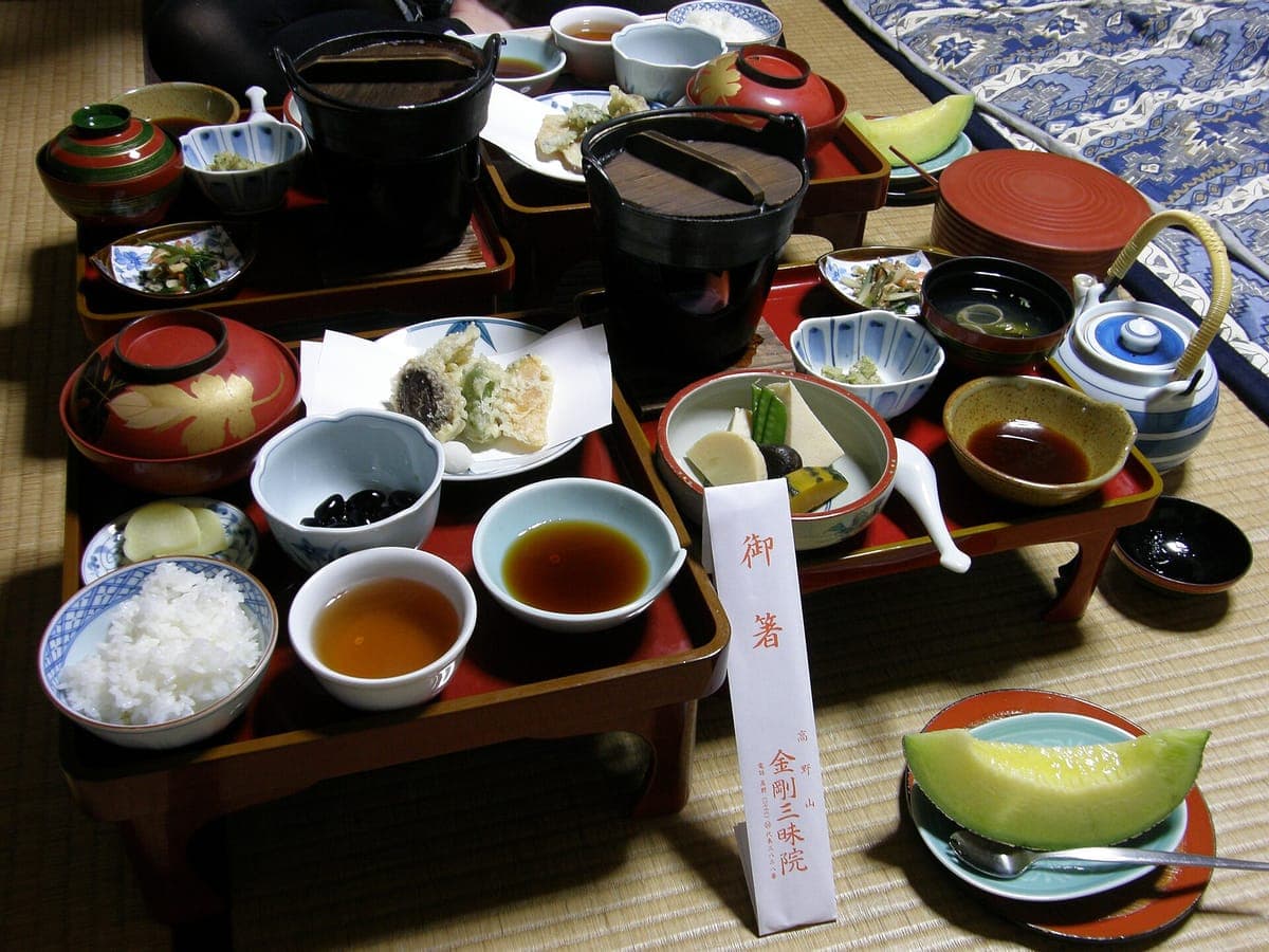 shōjin ryōri ужин, разложенный на красных лакированных подносах на татами в Kōyasan храмовом жилище, с темпурой, рисом, супом и небольшими гарнирами.