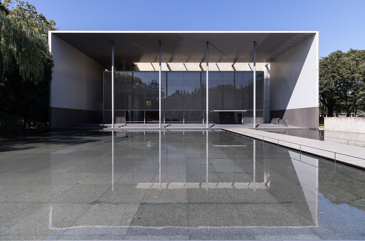 The modern Gallery of Hōryū-ji Treasures with a flat roof and glass front, reflected in a still, shallow pool surrounded by trees