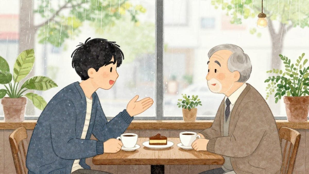 Seorang lelaki muda Korea bercakap dengan mentor Jepun yang lebih tua di meja kafe di tepi tingkap yang penuh dengan kehijauan, kedua-duanya bersandar dengan secawan kopi.