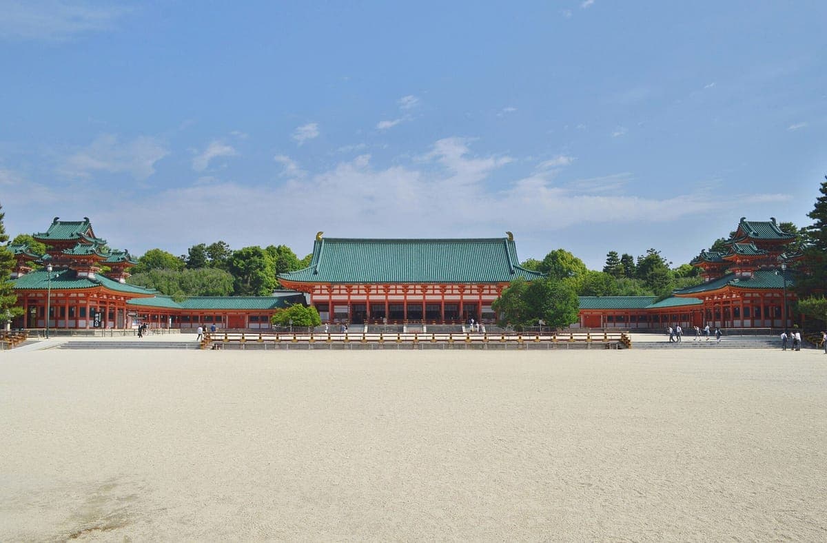 宽阔的白色砾石庭院通向蓝天下的平安殿Jingū,朱红色、绿顶的Daigokuden长殿