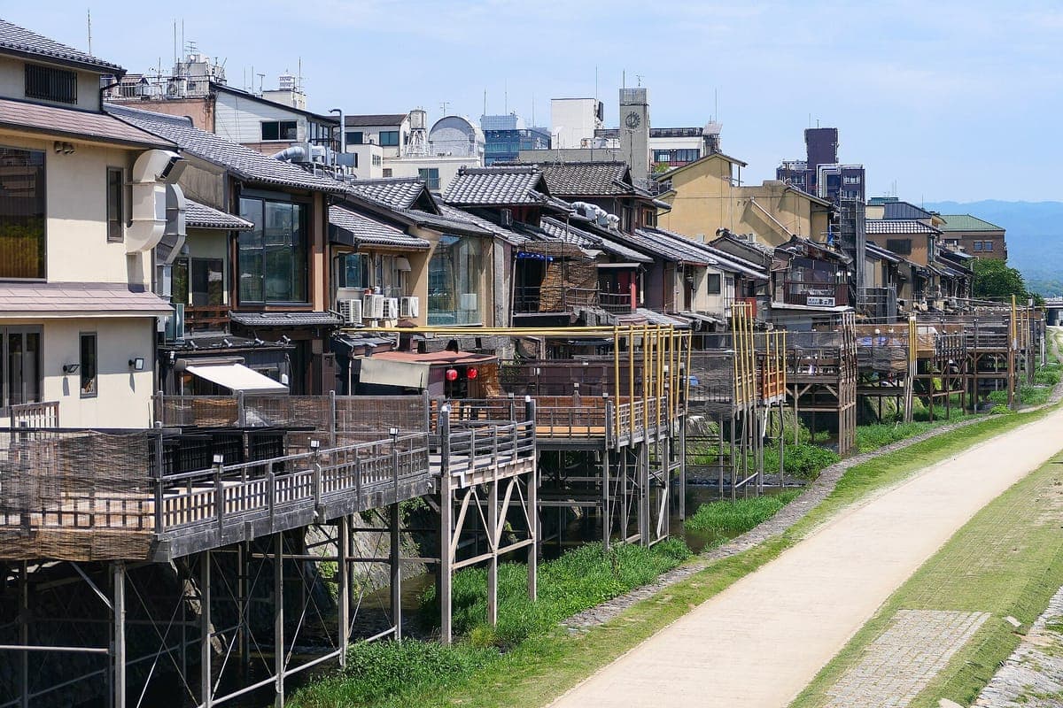 Nehir kenarındaki bir yolun yanında, Kyoto'daki Kamo Nehri kıyısındaki restoranlardan inşa edilmiş, sütunlar üzerinde bir dizi ahşap yemek platformu