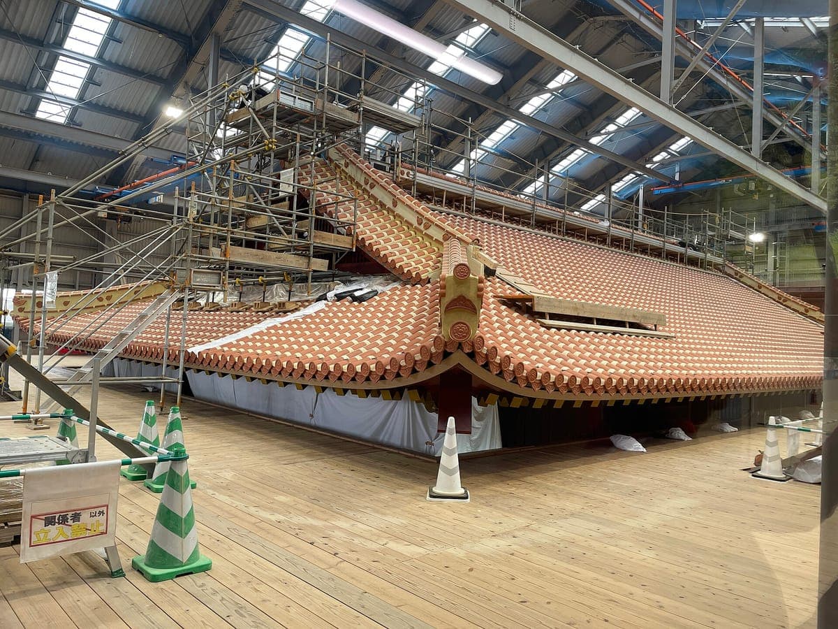 El techo parcialmente construido del Castillo Shuri Seiden dentro de una gran estructura de cobertura temporal, con andamios y una plataforma de madera.
