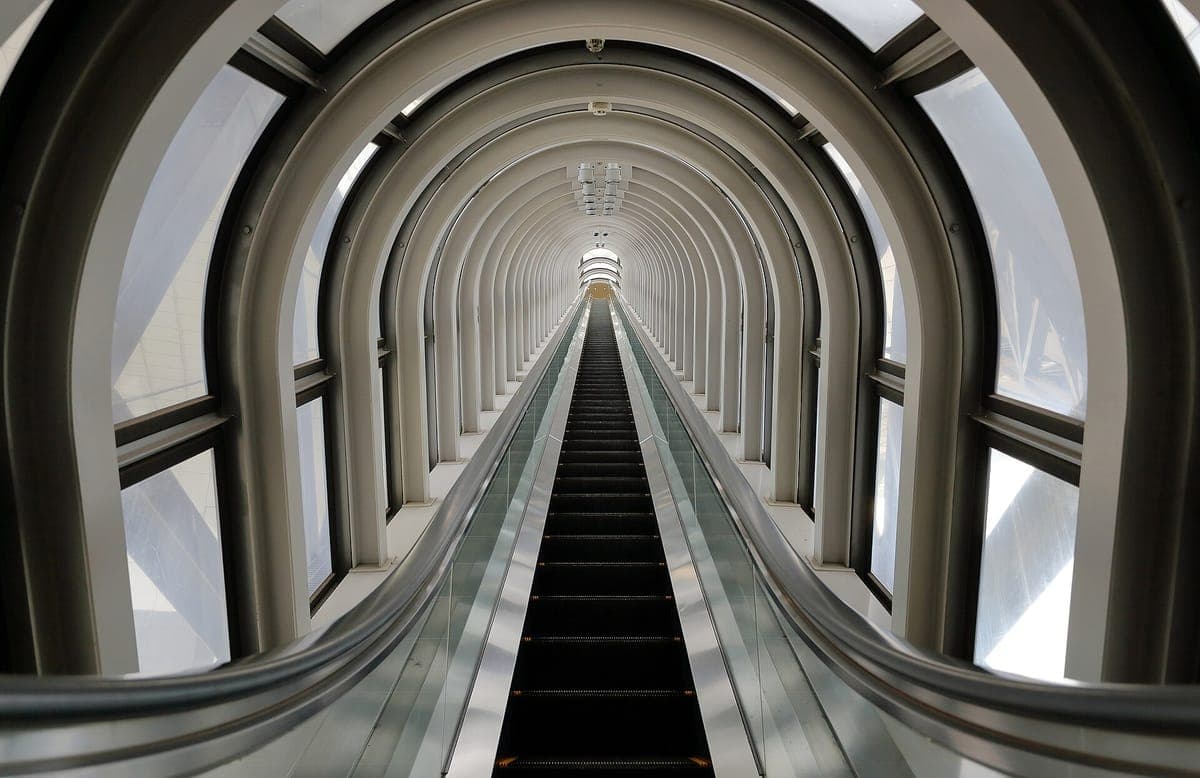 Una larga escalera mecánica que atraviesa un tubo de vidrio curvo con nervaduras arqueadas dentro del Umeda Sky Building
